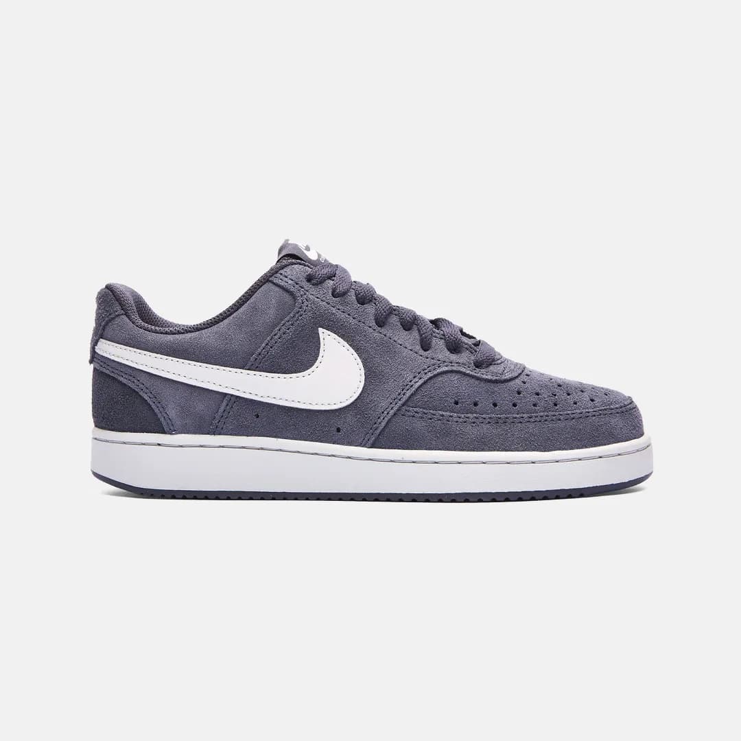 Mörkgrå Nike sneaker med vitt swoosh-emblem och vit sula, sedd från sidan på vit bakgrund.